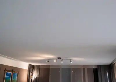 Moderne Wohnzimmerdecke mit stilvoller Beleuchtung und eleganten Vorhängen, die ein gemütliches Ambiente schaffen.