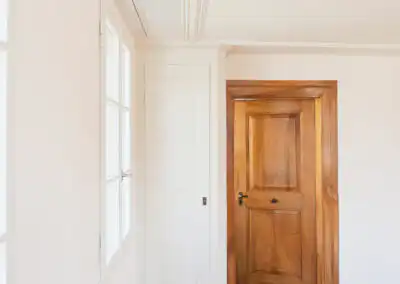 Helles Zimmer mit Holztür, weißem Wandschrank und Parkettboden. Innenarchitektur mit elegantem minimalistischen Design.