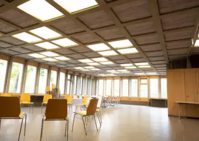 Heller, leerer Seminarraum mit gelben Stühlen und großen Fenstern, ideal für Meetings oder Veranstaltungen.