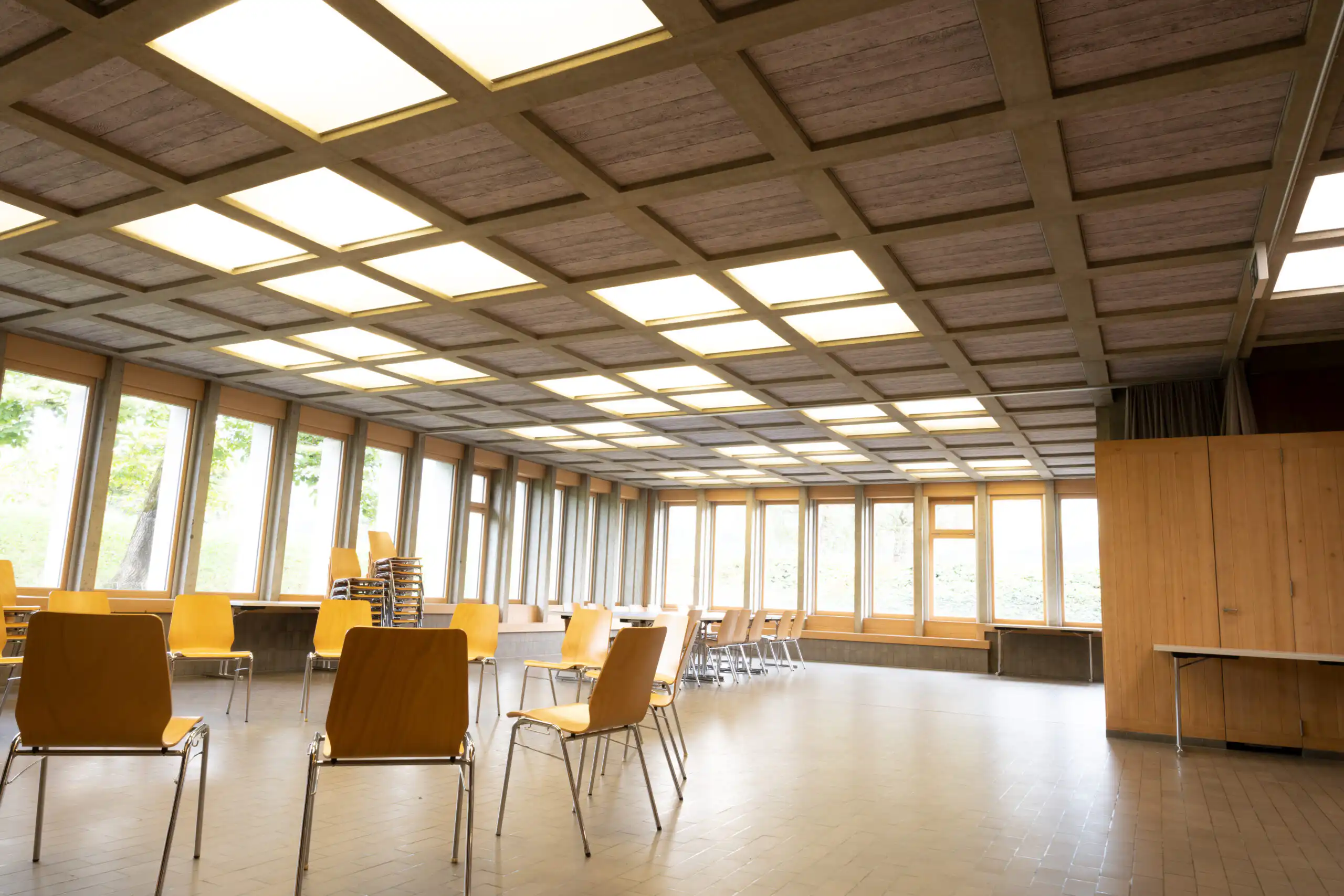 Heller, leerer Seminarraum mit gelben Stühlen und großen Fenstern, ideal für Meetings oder Veranstaltungen.