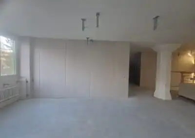 Unrenovierter Raum mit Trockenbauwänden, Fenster und Heizkörpern, bereit für Innenausbau.