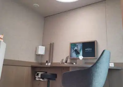 Moderner Raum mit Bildschirm, Stuhl und Tisch; minimalistisches Design, Büroatmosphäre mit neutralen Farben.