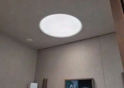 Runder Deckenlichtspot in modernem Raum mit grauer Wandverkleidung und Holzdetails für stilvolles Design.