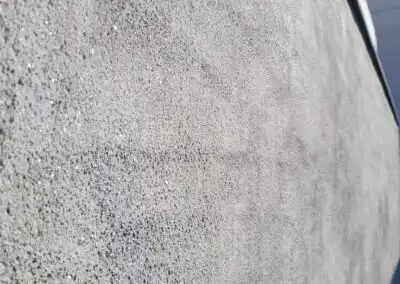 Grau strukturierte Betonwand mit unregelmäßiger Oberflächenstruktur in Nahaufnahme unter Tageslicht.