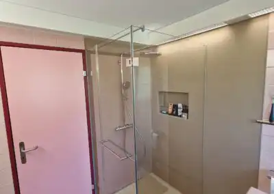 Moderne Dusche mit Glaswand und rosa Tür in elegantem Badezimmer.