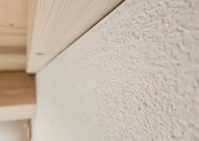 Nahaufnahme einer strukturierten weißen Wand mit Holzdecke für modernes Innendesign und Ästhetik.