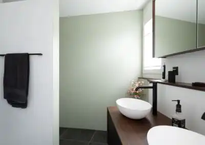 Modernes Badezimmer mit Doppelwaschbecken, Holzablage und schwarz-weißer Farbpalette.