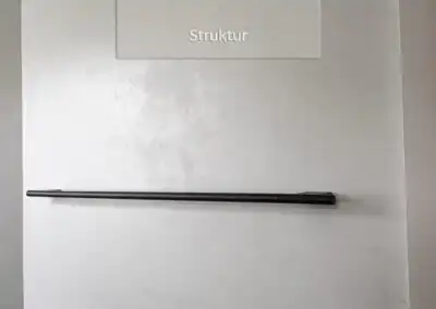 Wand mit sichtbarer Struktur, schwarzer Handtuchhalter und Lichtschalter, minimalistische Badezimmergestaltung.