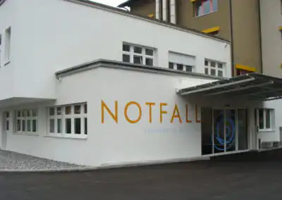 Eingang zur Notfallaufnahme des Kantonsspitals Obwalden, modernes Gebäude mit großen Fenstern und Vordach.