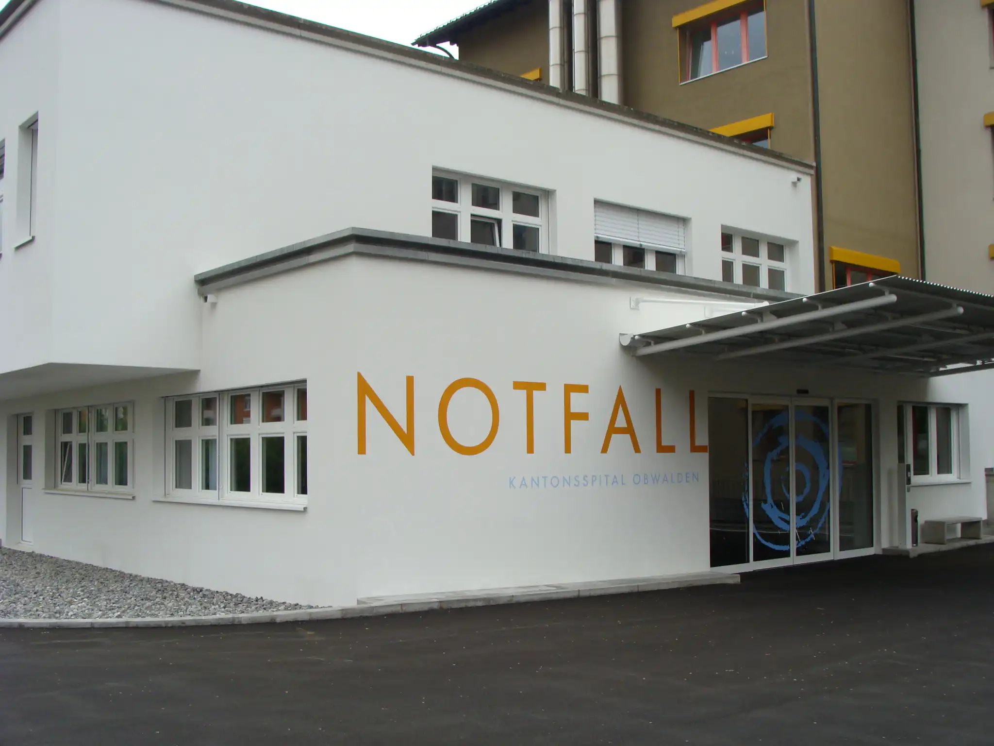 Eingang zur Notfallaufnahme des Kantonsspitals Obwalden, modernes Gebäude mit großen Fenstern und Vordach.