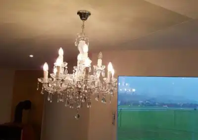 Kronleuchter mit kristallklaren Details hängt in elegantem Raum mit großem Fenster und grüner Aussicht.